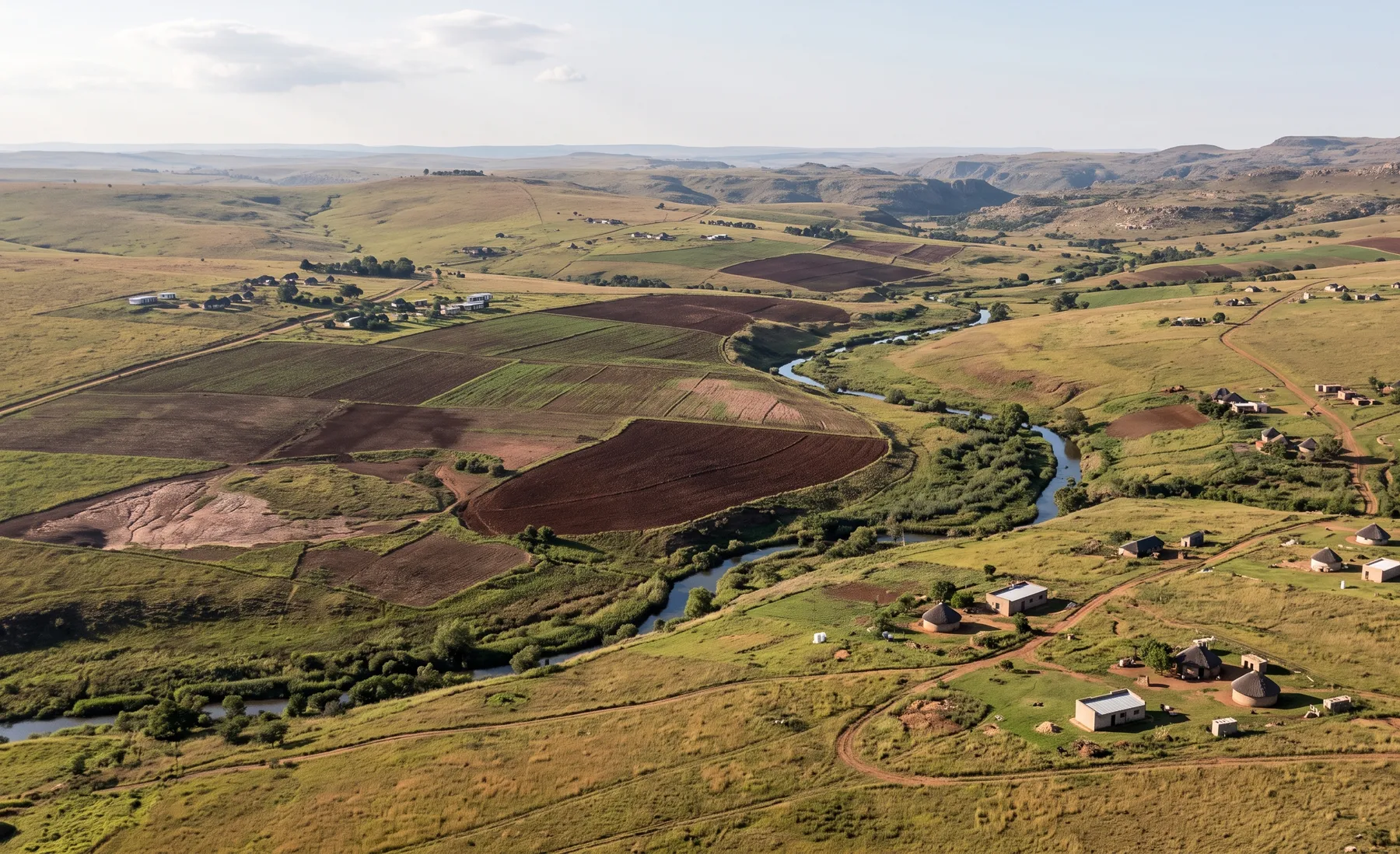 An elevated view of a mixed land-use catchment with cultivated fields, grassland veld, and scattered homesteads.