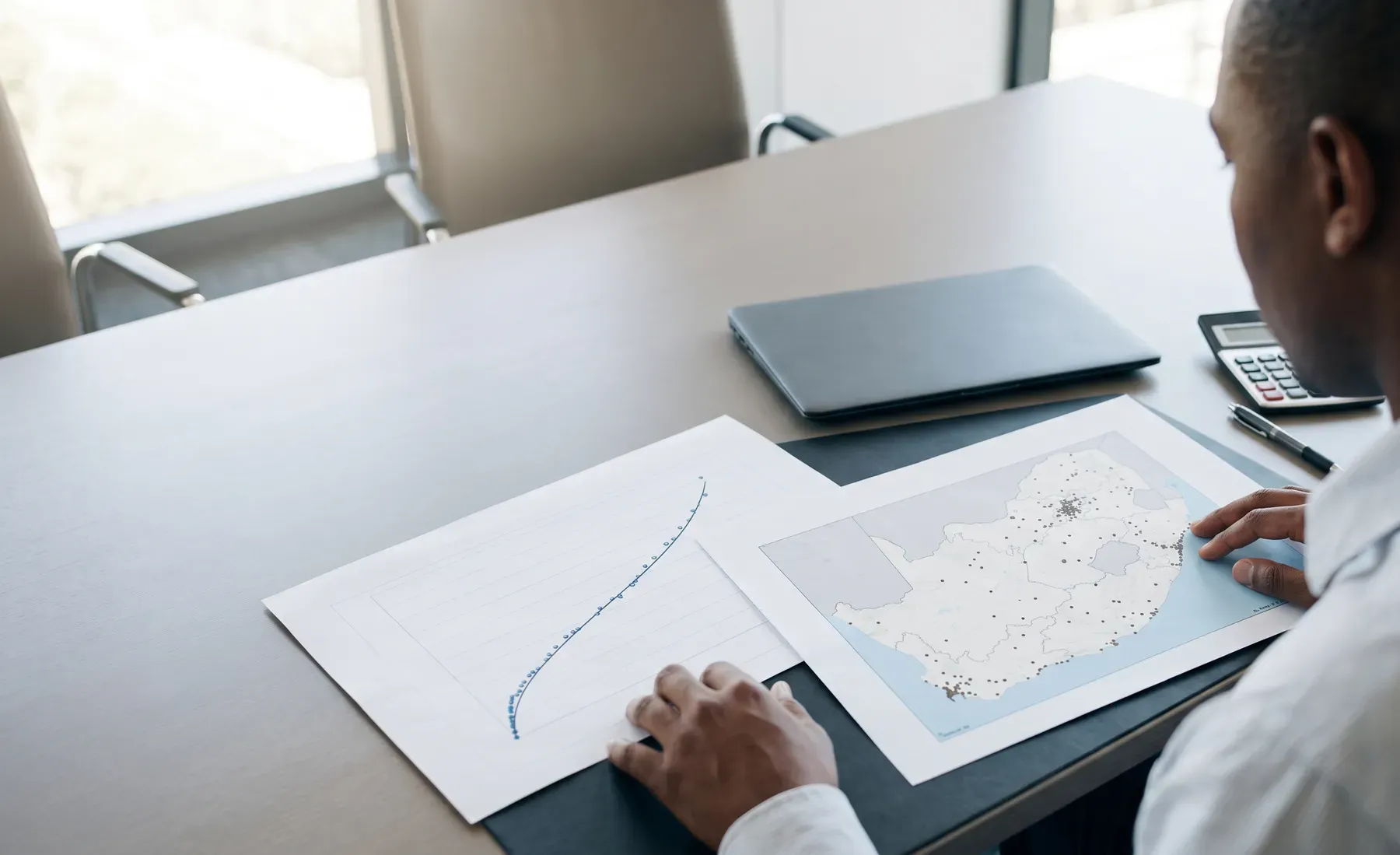 An analyst reviewing flood loss exceedance-probability curves alongside a portfolio exposure map.