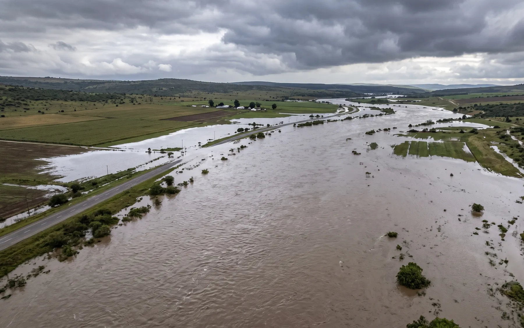 A river in high flood spreading across its natural floodplain, showing the extent of a rare flood event.
