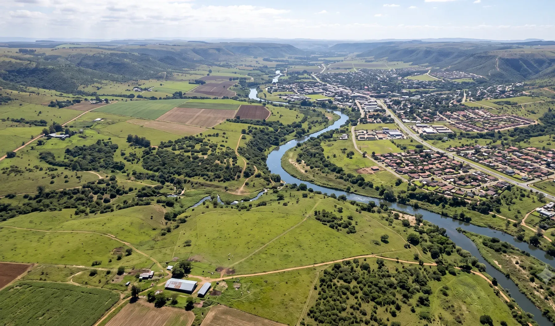 An elevated view of a river valley catchment showing the watercourse winding through mixed rural and urban land use.
