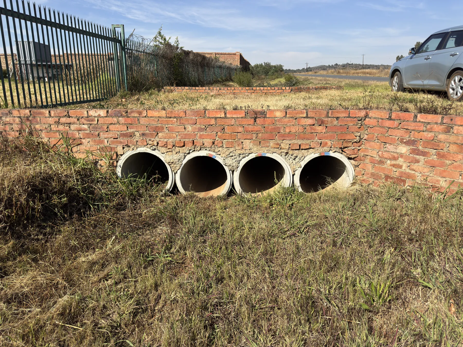 Four-barrel concrete pipe culvert set in a brick headwall beside a rural South African road.