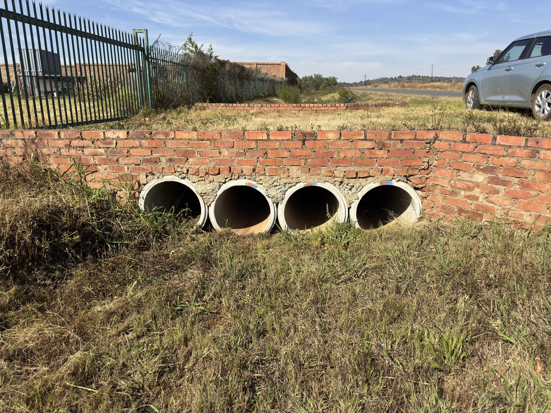 Four-barrel concrete pipe culvert set in a brick headwall beside a rural South African road.