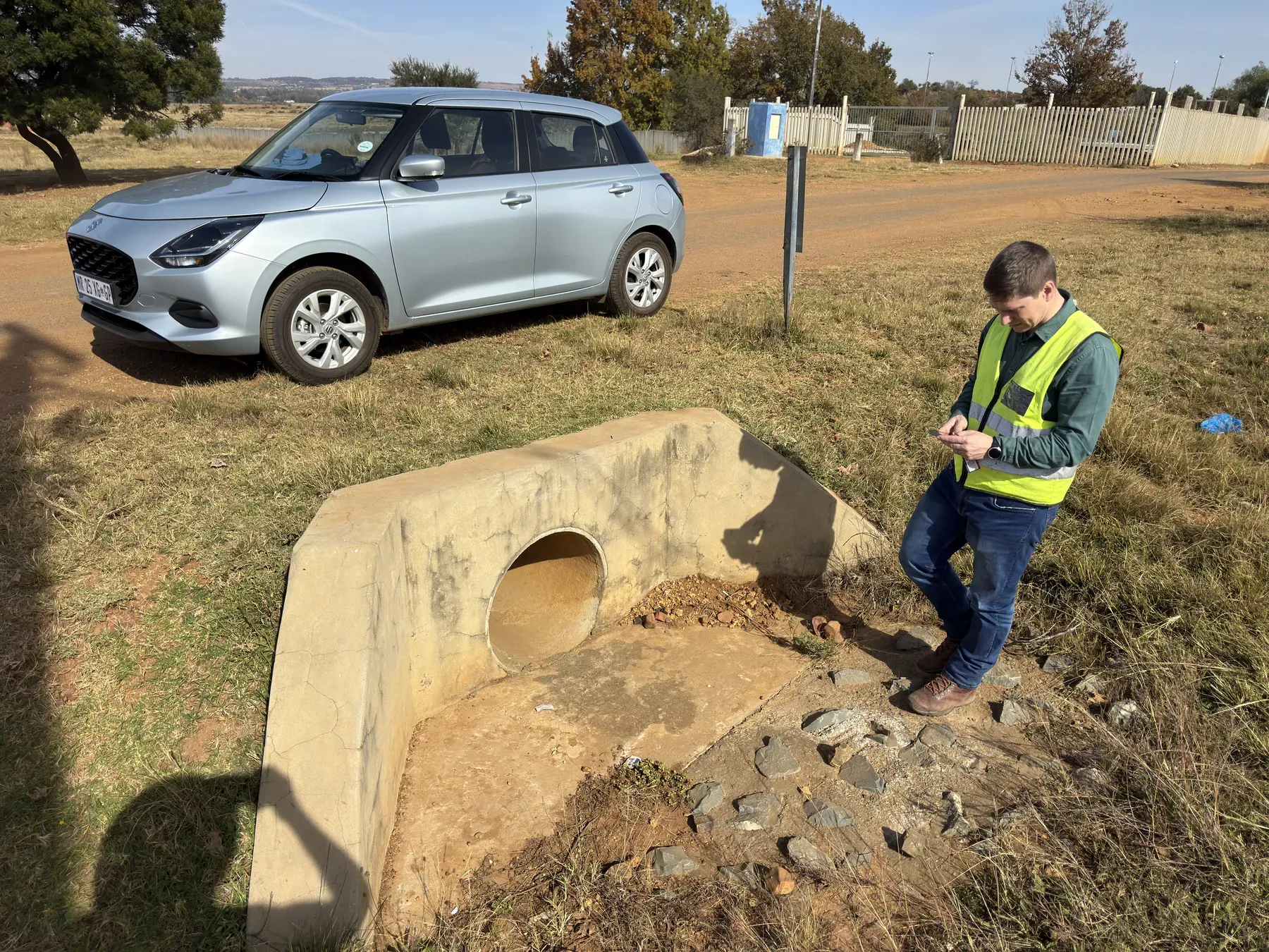 An engineer inspecting the inlet and barrel of a concrete culvert.