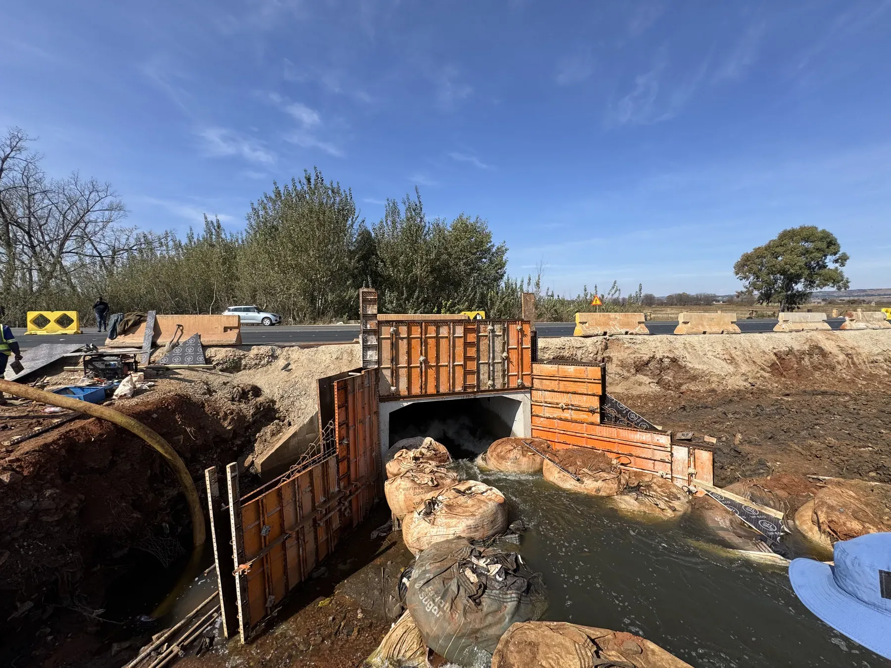 A newly constructed multi-cell concrete box culvert under a road embankment.